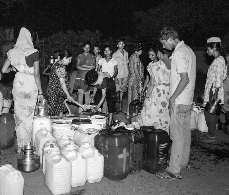 Women, men and children queuing to collect drinking water late in the night at a group connection in Mumbai, Maharashtra